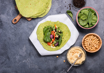 Making vegan tortilla wraps for healthy snack, tortillas with cheakpeas, hummus, beluga lentils and spinach