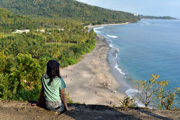 Indonesian girl watching Senggigi Beach at sunset, Lombok, Indonesia