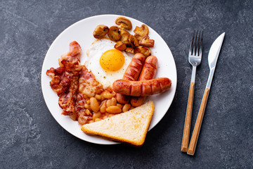 Top view flatlay with classical english breakfast with fried bacon, mushrooms and eggs. Served with black coffee.