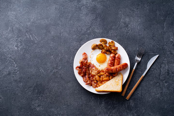 Top view flatlay with classical english breakfast with fried bacon, mushrooms and eggs. Served with black coffee.