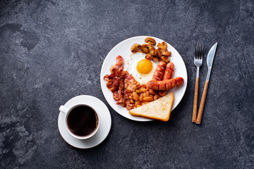 Top view flatlay with classical english breakfast with fried bacon, mushrooms and eggs. Served with black coffee.