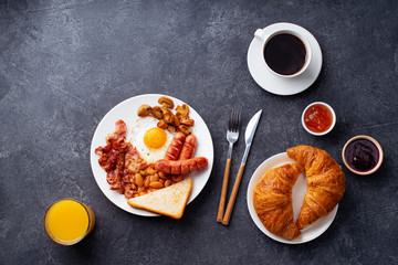 Classical english breakfast with fried bacon, mushrooms and eggs. Served with orange juice, croissants and black coffee.