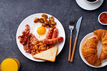 Classical english breakfast with fried bacon, mushrooms and eggs. Served with orange juice, croissants and black coffee.