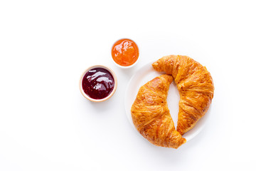 Top view flatlay with fresh croissants served with jams and buter. Morning meal concept. White...