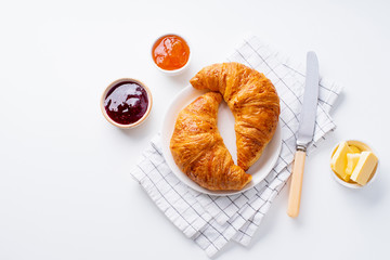 Top view flatlay with fresh croissants served with jams and buter. Morning meal concept. White background