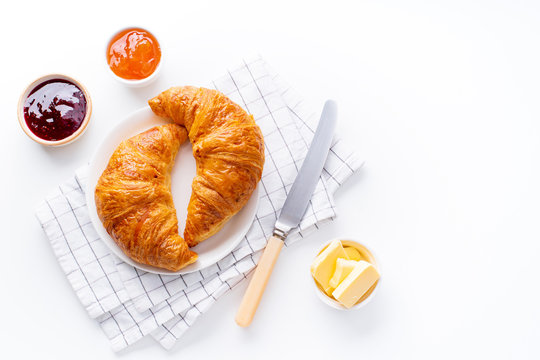 Top view flatlay with fresh croissants served with jams and buter. Morning meal concept. White background