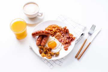 Overhead image of classical english breakfast with fried bacon, mushrooms and eggs. Served with orange juice and coffee.