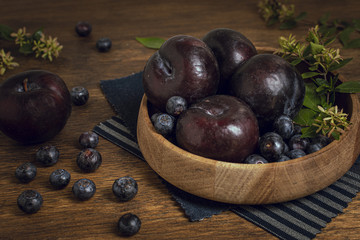 Fresh healthy bowl full of plums and blueberries