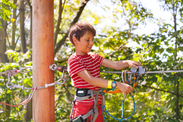 Obraz premium Happy boy learn to use zip line trolley, rope park