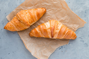 Croissants with paper on a gray concrete background. View from above. Top view.