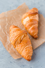 Croissants with paper on a gray concrete background. View from above. Top view.