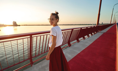 Bright summer lifestyle portrait of young pretty woman in eyewear, red skirt and white T-shirt,...
