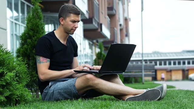 Freelancer work on laptop in the open air while sitting on grass, free business