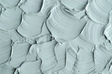 Gray cosmetic clay (facial bentonite mask, cream, scrub, body wrap) texture close up. Abstract background with brush strokes.