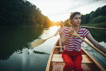 Couple paddle the boat on the sunset lake