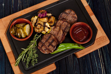 juicy, fried, tender steak with vegetables and sauces on a special stand