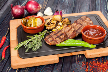 juicy, fried, tender steak with vegetables and sauces on a special stand