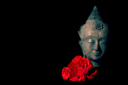 Peace and love. Traditional meditating Buddha head with red roses
