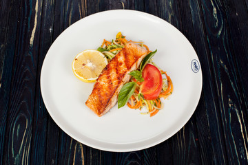 appetizing fried fish, beautifully laid out with greens and vegetables on a dish, for designer solutions in cooking
