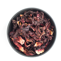 Dried hibiscus petals in dark bowl isolated on white background. Red tea, karkade. Top view