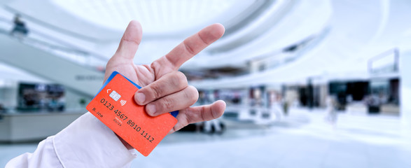 Hand of rocker with shirt holding two credit card on mall