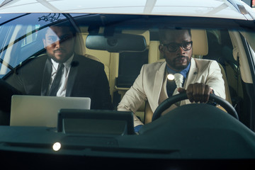 two business partners working together in front seat of car at evening dark time