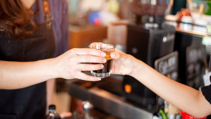 Close up of female hand is taking hot coffee from Barista