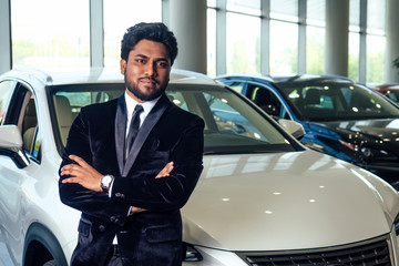 happy business indian man in well-dressed black suit buy new biodiesel eco automobile in lux...