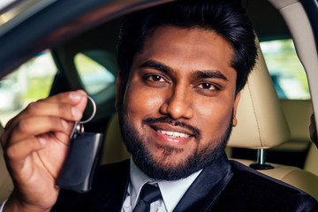 indian cheerful car salesman showing new keys showroom