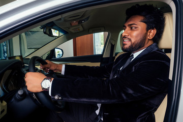 happy business indian man in well-dressed black suit buy new biodiesel eco automobile in lux...