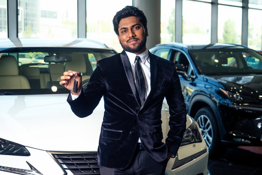 indian cheerful car salesman showing new keys showroom