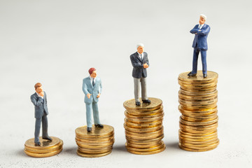 Successful businessman with big profits at the top of the stairs by coins and less successful businessmen with small companies. Adequate investment in the company.