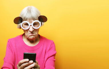 old grandmother is talking to her grandchildren by phone, smiling and greeting them.