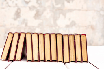 Stack of old ancient shabby books on a white wooden background.