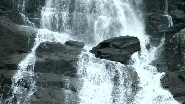 Slow-motion footage of falling water on stones at Skok Waterfall in Slovakia. Spraying torrents of water rushing down.