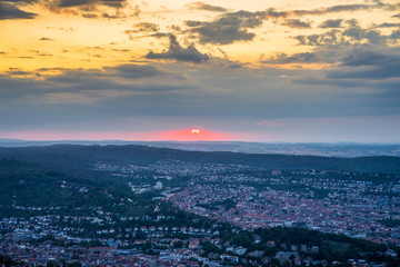 Fototapeta na wymiar Germany, Red sky at sunset in summer over cityscape of city stuttgart, aerial perspective above houses, roofs and buildings