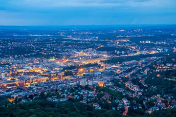 Deutschland, Magisch beleuchtete Lichter der Stuttgarter Stadthäuser, Gebäude, Straßen und Kräne bei Nacht aus der Luftperspektive © Simon Dux Media