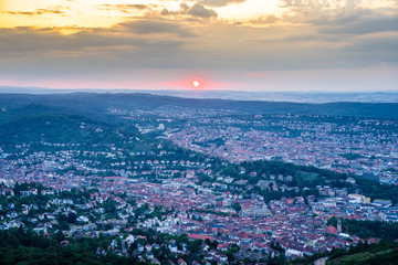 Fototapeta na wymiar Germany, Orange sky sunset in summertime over city stuttgart, aerial view above houses, roofs and buildings in the evening