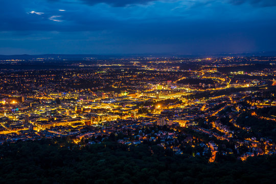 Fototapeta Germany, Orange night lights illuminating stuttgart city skyline from above aerial view in summer in magical atmosphere