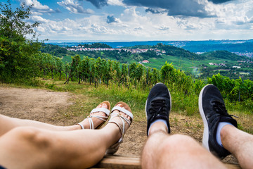 Germany, Legs of a couple resting on top of kappelberg mountain enjoying breathtaking view over...