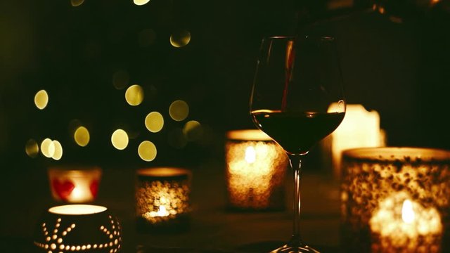 Wine pouring into a glass on the background of Christmas tree in the evening dark. New Year holidays beverage concept image.