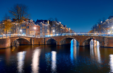Obraz premium Architecture and canals with bridges at night in Amsterdam.