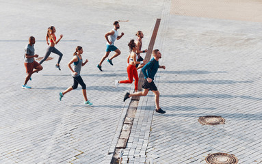Full length top view of young people in sports clothing jogging while exercising outdoors
