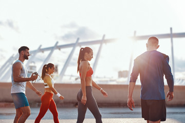 Group of young people in sports clothing walking together outdoors