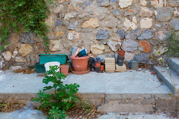 Fototapeta na wymiar Many old dirty flower pots stand near a stone wall in the backyard