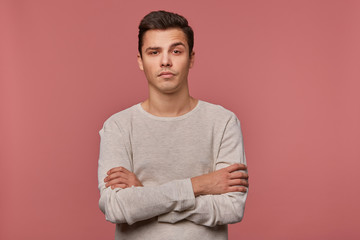 Young handsome unhappy guy wears in checkered shirt, looks at the camera with disgusted expression,...