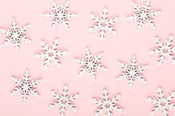 Christmas background. White snow decorations on a pink background.