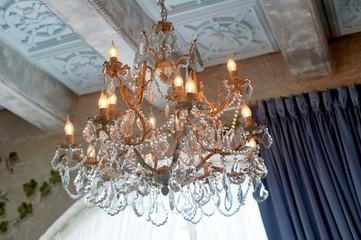 Crystal chandelier under the ceiling in the loft-style room, light brick.