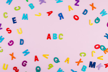 Fototapeta na wymiar Back to school concept. Bright multicolored alphabet background. Colorful wooden letters on pink background. Isolated, Flat Lay, Copy space, top view