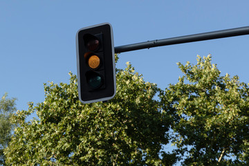 Hanging traffic light with yellow light on